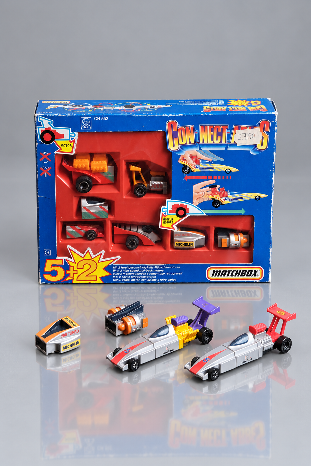 Matchbox Connectables 5+2 Set CN 552 in blauer Originalverpackung mit zusätzlichen Rennwagen und Einzelteilen auf grauem Hintergrund.